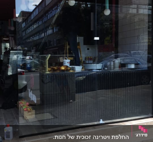 חלון זכוכית גדול עם השתקפות רחוב ומכוניות